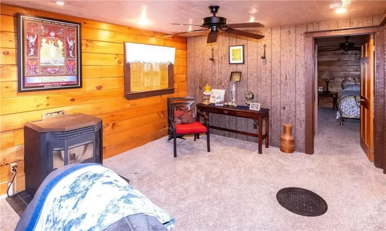 Sitting room with wooden walls, ceiling fan, and carpet flooring