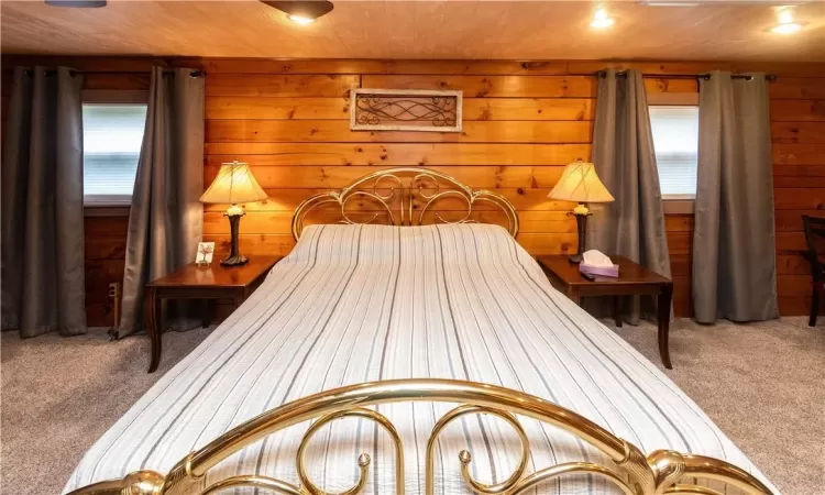 Carpeted bedroom featuring wooden walls and wood ceiling