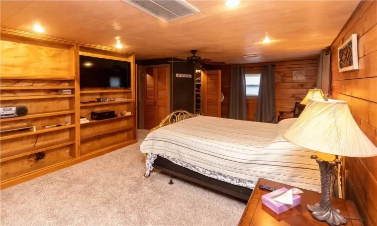 Bedroom with wooden walls, carpet floors, and wooden ceiling