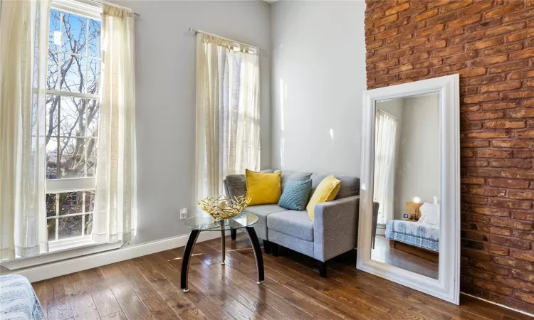 Living area featuring brick wall and dark hardwood / wood-style flooring