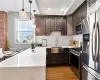 Kitchen featuring stainless steel appliances, sink, hanging light fixtures, dark brown cabinets, and dark hardwood / wood-style flooring