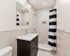 Bathroom with a shower with curtain, vanity, toilet, and tile walls