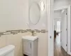 Bathroom with hardwood / wood-style flooring, vanity, toilet, and tile walls