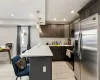 Kitchen featuring kitchen peninsula, appliances with stainless steel finishes, a breakfast bar area, pendant lighting, and decorative backsplash