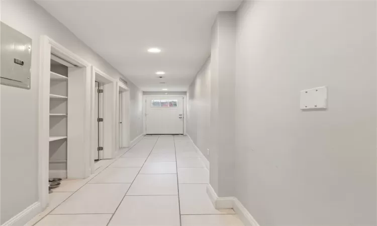 Hallway with electric panel and light tile patterned floors