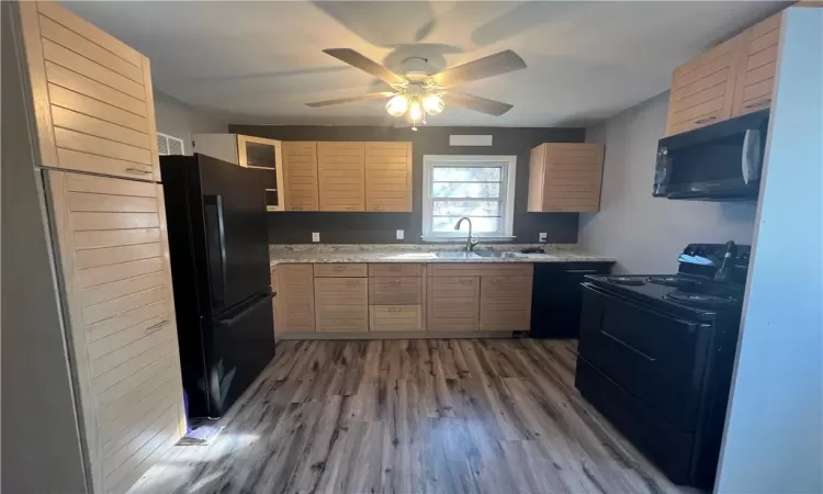 Kitchen with light brown cabinets, dark wood-type flooring, sink, black appliances, and ceiling fan