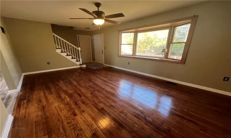 Empty room with ceiling fan and dark hardwood / wood-style flooring