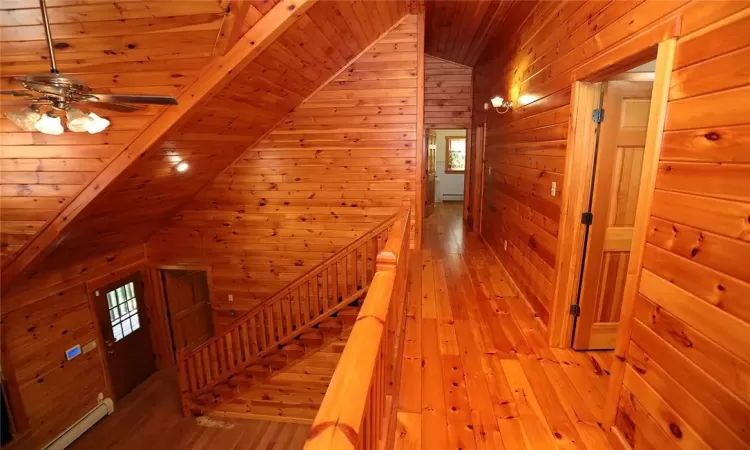 Hall featuring wood walls, plenty of natural light, and baseboard heating