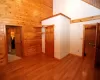 Unfurnished bedroom with wood walls, light wood-type flooring, a closet, high vaulted ceiling, and a baseboard heating unit