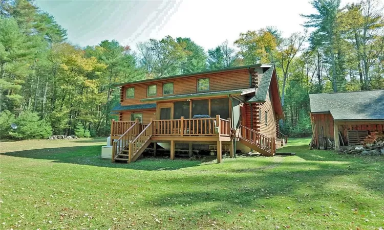 Back of property with a wooden deck and a lawn