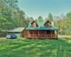 Log cabin with a garage, an outbuilding, a front lawn, and covered porch