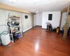 Basement featuring a paneled ceiling, wood-type flooring, electric panel, and a baseboard heating unit