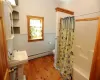 Bathroom featuring wood-type flooring, shower / tub combo, toilet, and a baseboard heating unit