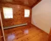 Guest bedroom with wood ceiling, a baseboard heating unit, light wood-type flooring, and a healthy amount of sunlight