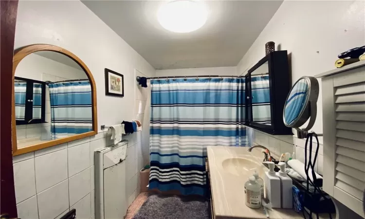 Bathroom featuring vanity, a shower with curtain, and tile walls