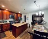 Kitchen with hardwood / wood-style flooring, black fridge, pendant lighting, a chandelier, and range with gas cooktop