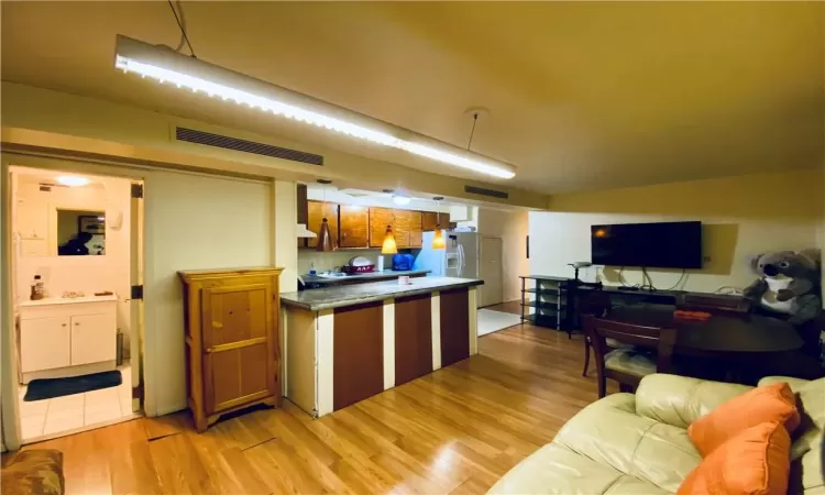 Kitchen featuring white fridge with ice dispenser and light hardwood / wood-style flooring