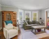 Living room with plenty of natural light, dark wood-type flooring, and crown molding