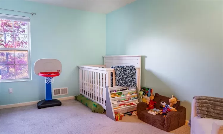 Carpeted bedroom with multiple windows and a crib