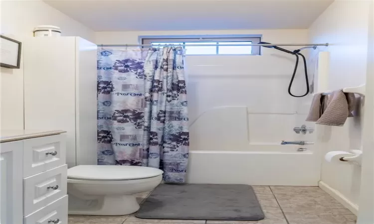 Full bathroom with vanity, shower / bath combo, toilet, and tile patterned flooring