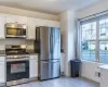 Kitchen with white cabinets, dark stone countertops, stainless steel appliances, and light tile patterned floors