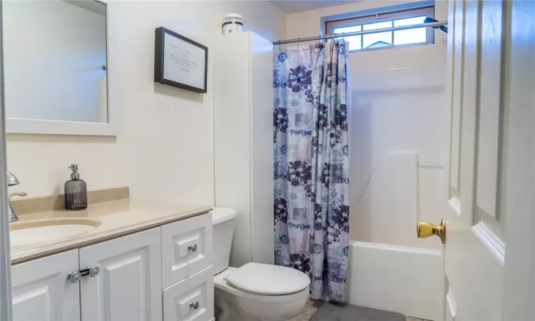 Full bathroom with vanity, shower / bath combo with shower curtain, and toilet