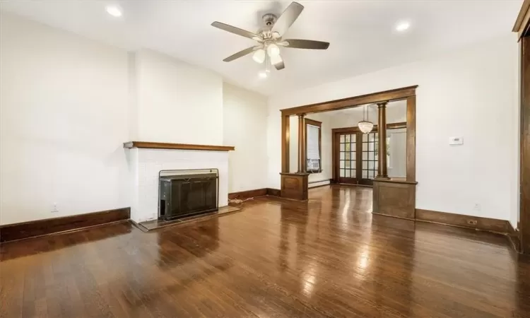 living room with hard wood floor and original wood trimmings and new fireplace.  Shows entry to dinning room.