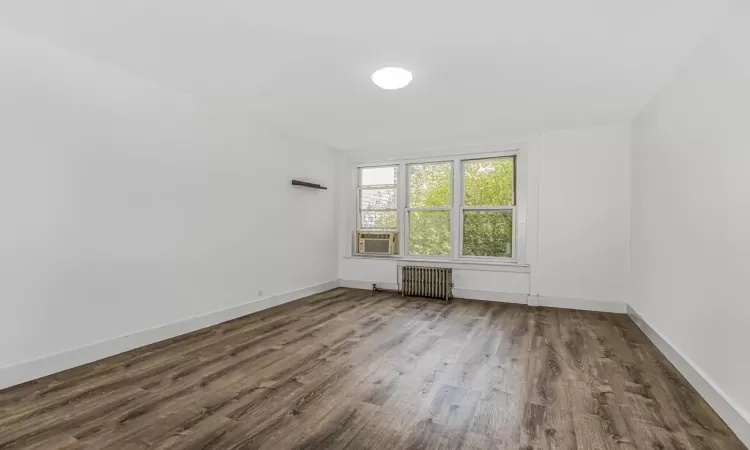 Unfurnished room featuring hardwood / wood-style floors and radiator