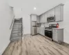 Kitchen with light wood-type flooring, tasteful backsplash, stainless steel appliances, and gray cabinetry