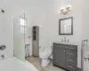 Bathroom featuring toilet, vanity, tile patterned flooring, and tile walls