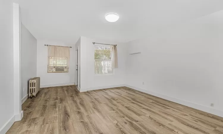 Unfurnished room with light hardwood / wood-style floors and radiator