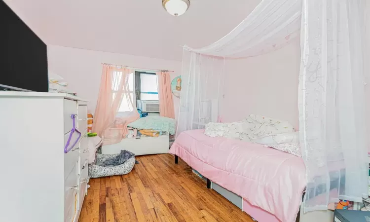 Bedroom with cooling unit and light wood-type flooring