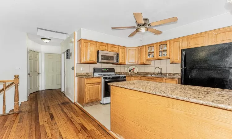 Kitchen featuring tasteful backsplash, sink, black fridge, white gas range, and light hardwood / wood-style floors