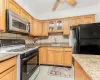 Kitchen featuring white range with gas cooktop, tasteful backsplash, black fridge, light stone countertops, and sink