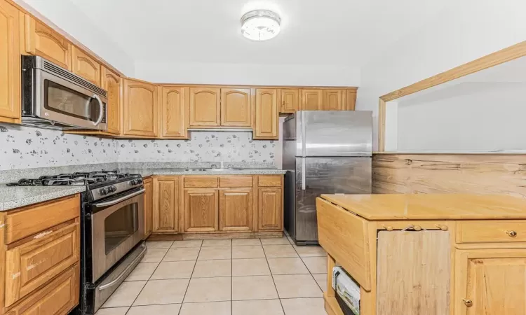 Kitchen featuring stainless steel appliances, sink, and light tile patterned flooring