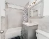 Full bathroom with vanity, tile walls, shower / tub combo, and toilet