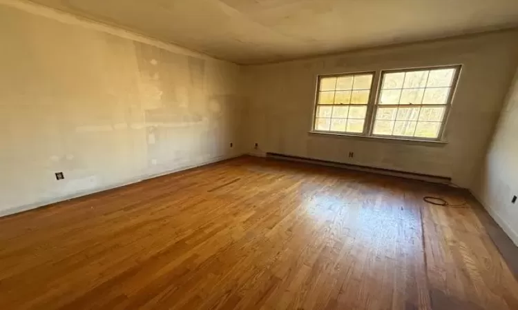 Spare room featuring hardwood / wood-style floors and a baseboard heating unit