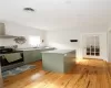 Kitchen featuring stainless steel electric stove, sink, light hardwood / wood-style floors, wall chimney exhaust hood, and green cabinetry