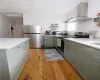 Kitchen with appliances with stainless steel finishes, extractor fan, and light wood-type flooring