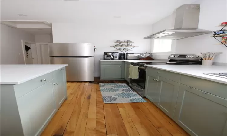 Kitchen with appliances with stainless steel finishes, extractor fan, and light wood-type flooring