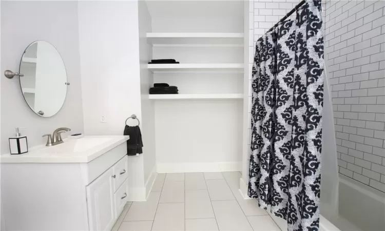 Bathroom featuring vanity, shower / bath combo with shower curtain, and tile patterned flooring