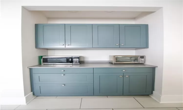 Bar with blue cabinets and light tile patterned floors