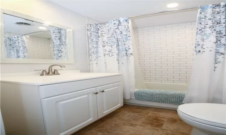 Full bathroom with vanity, shower / tub combo, and toilet