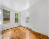 Empty room with light hardwood / wood-style floors and a baseboard heating unit