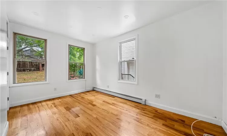 Empty room with light hardwood / wood-style floors and a baseboard heating unit