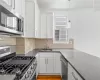 Kitchen featuring white cabinetry, tasteful backsplash, stainless steel appliances, and sink