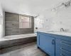 Bathroom featuring tiled shower / bath, vanity, and tile walls