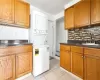 Laundry area with stacked washer and dryer, light tile patterned flooring, a textured ceiling, and sink