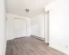 Unfurnished bedroom featuring a baseboard radiator, light hardwood / wood-style flooring, and a closet