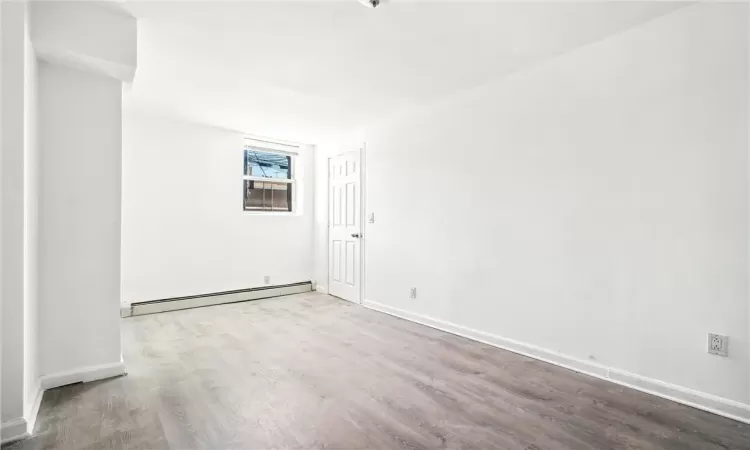 Empty room with baseboard heating and hardwood / wood-style floors